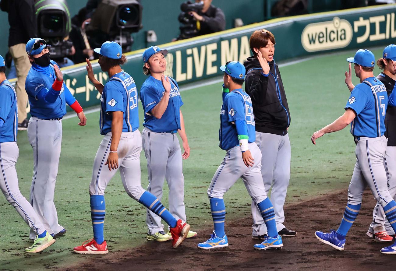 阪神対日本ハム　阪神に勝利した新庄監督（左）と伊藤（左から3人目）はナインとハイタッチする（撮影・上田博志）