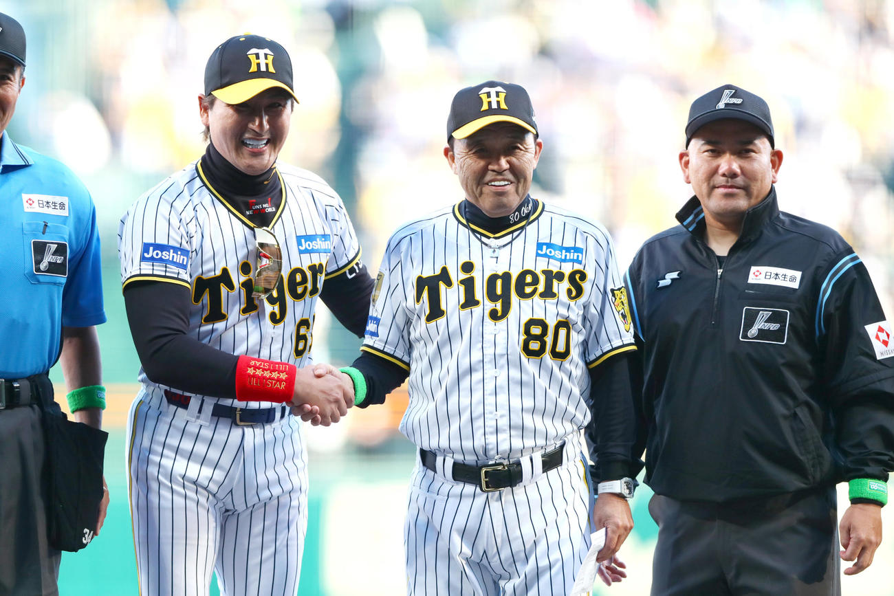 阪神対日本ハム　試合前のメンバー表最終確認で日本ハム新庄監督（左）は阪神のユニホームを着て阪神岡田監督と握手をかわす（撮影・上山淳一