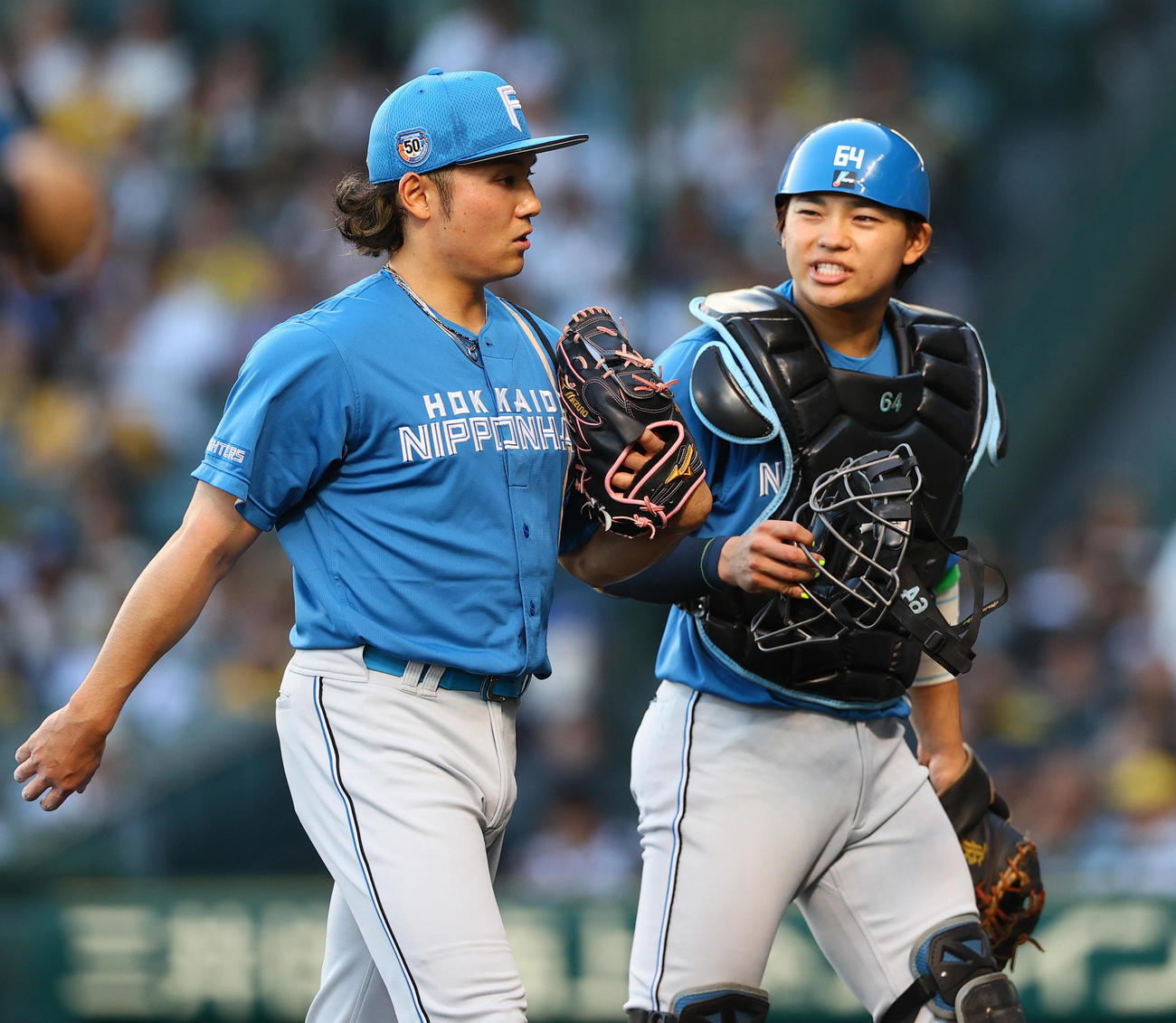 阪神対日本ハム　初回の投球を終えた日本ハム先発の伊藤（左）と話しながらベンチへ引き揚げる捕手田宮（撮影・上山淳一）