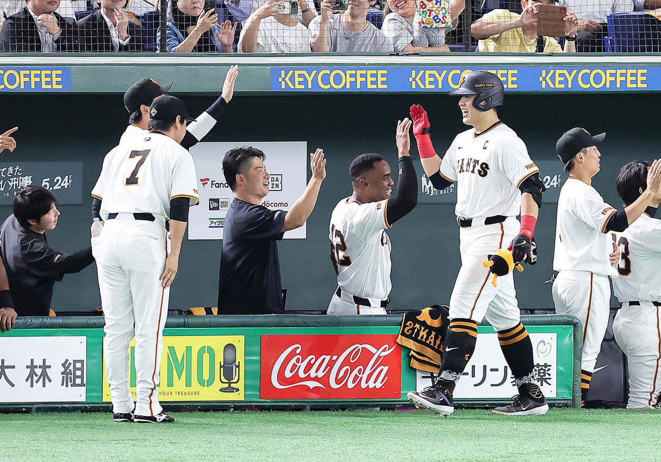 巨人対ソフトバンク　3回裏巨人1死二塁、岡本和（右）は逆転の左越え2点本塁打を放ち長野（左）らの出迎えに笑顔を見せる（撮影・足立雅史）