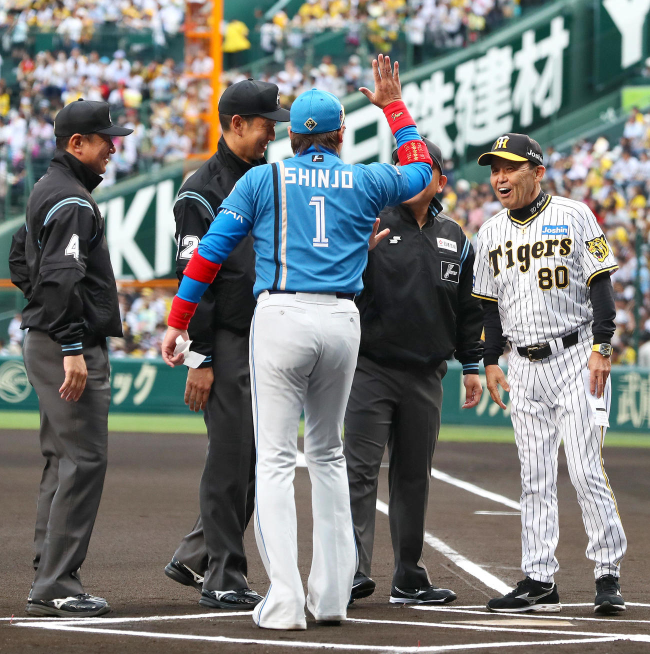 阪神対日本ハム　メンバー表の最終確認で日本ハム新庄監督（左）は審判団とハイタッチ。右は笑顔も静観する阪神岡田監督（撮影・上山淳一）