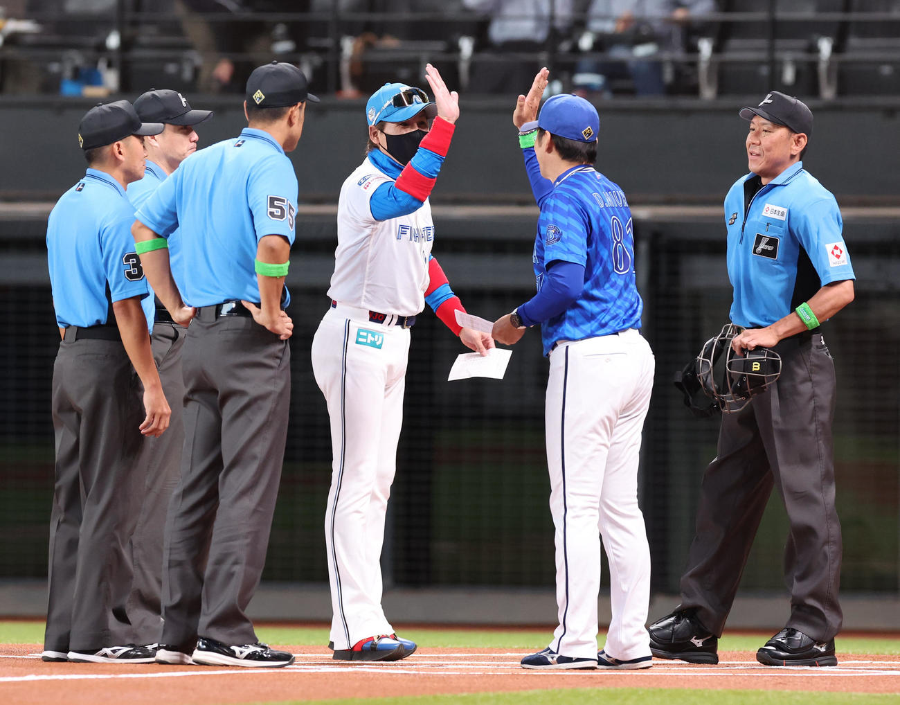 日本ハム対DeNA　試合前、メンバー表を交換しハイタッチをする日本ハム新庄監督（中央）とDeNA三浦監督（撮影・佐藤翔太）