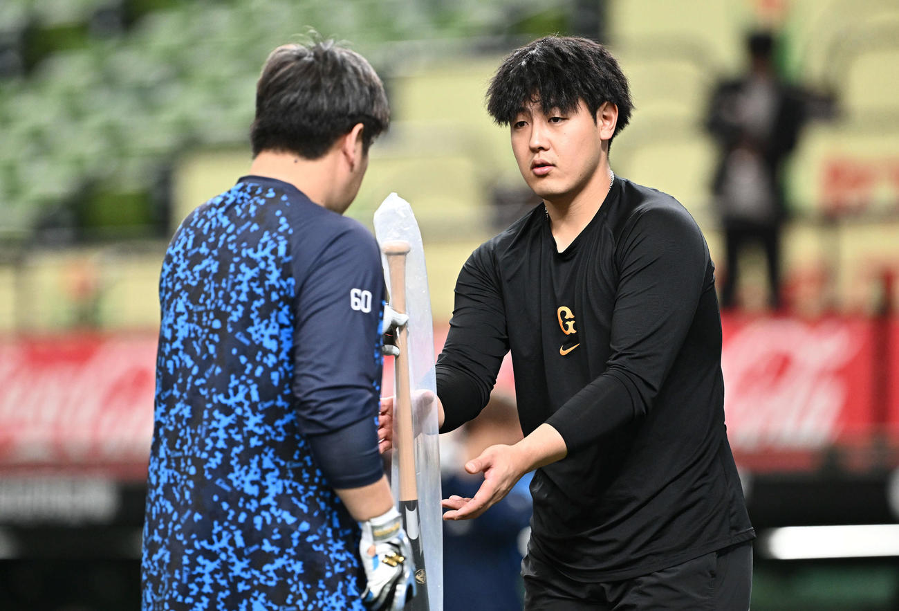 西武対巨人　試合前練習で西武中村剛（左）からバットを受け取る巨人岡本和（撮影・滝沢徹郎）