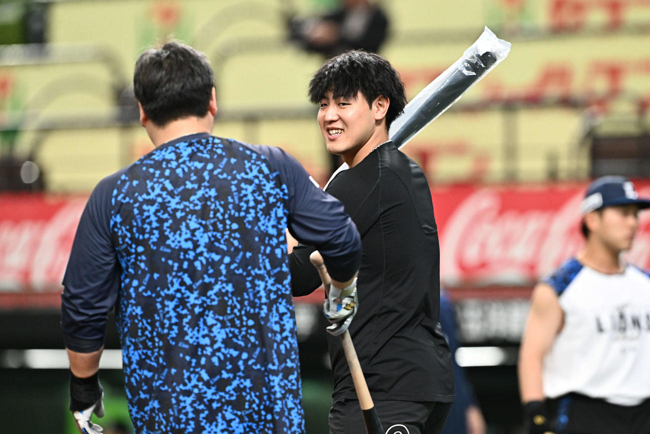 西武対巨人　試合前練習で西武中村剛（左）からバットを受け取り笑顔の巨人岡本和（撮影・滝沢徹郎）