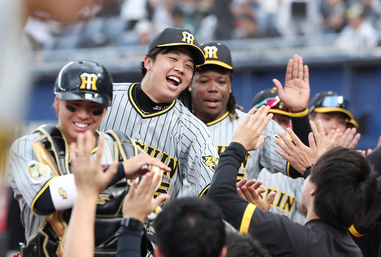 ロッテ対阪神　完封勝利で連敗を止め、ナインらとタッチを交わして喜ぶ、左から梅野、才木、ミエセス（撮影・前田充）