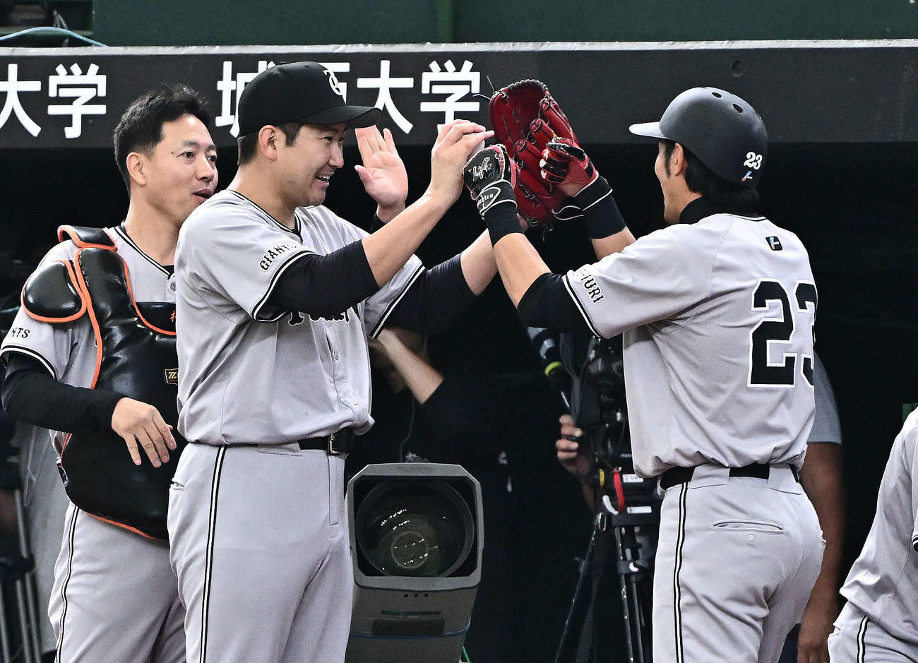 西武対巨人　5回表巨人2死二塁、丸の適時打で生還した立岡（右）とタッチをかわす菅野（撮影・滝沢徹郎）