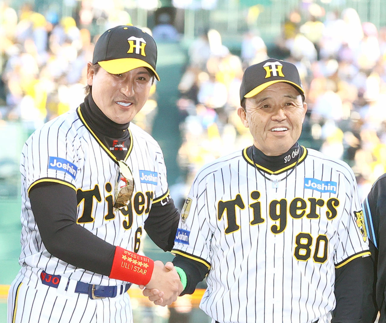 試合前のメンバー表確認で日本ハム新庄監督（左）は、阪神のユニホームを着て岡田監督と握手をかわす（2024年5月29日撮影）