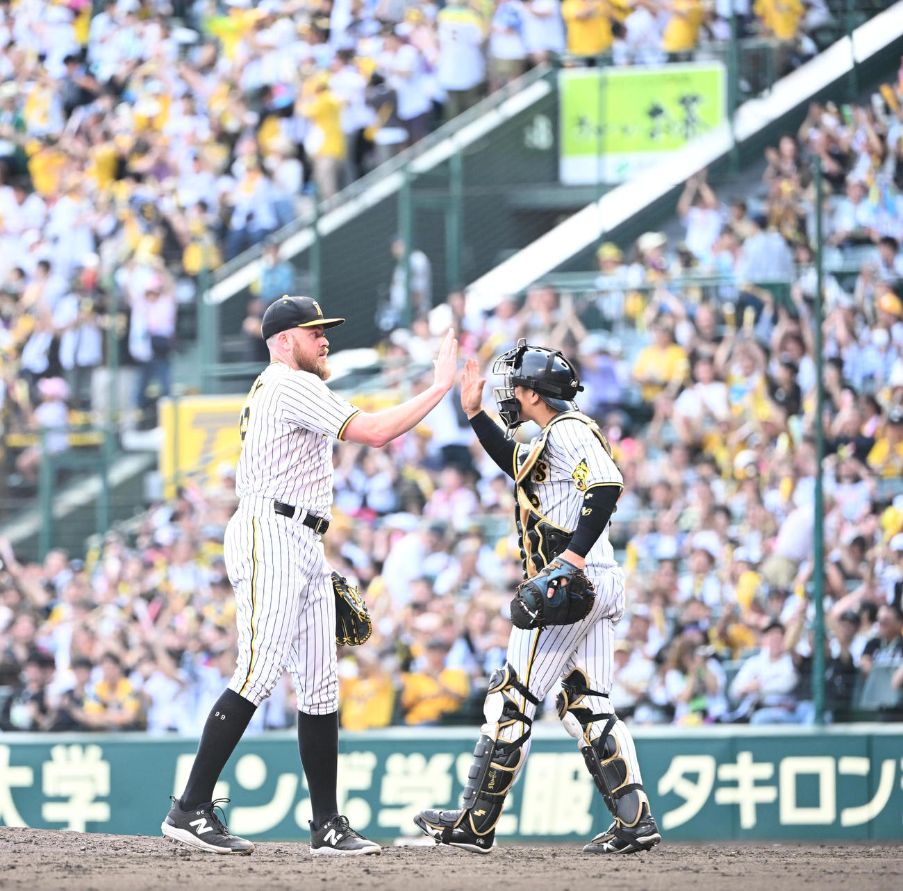 阪神対西武　1失点で完投勝利を飾ったビーズリーは捕手梅野（右）とハイタッチし喜び合う（撮影・和賀正仁）
