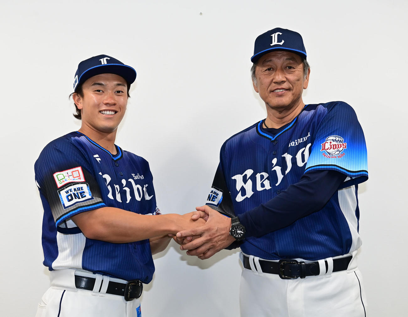 支配下選手契約を結び渡辺監督代行（右）と握手を交わす西武奥村（撮影・和賀正仁）