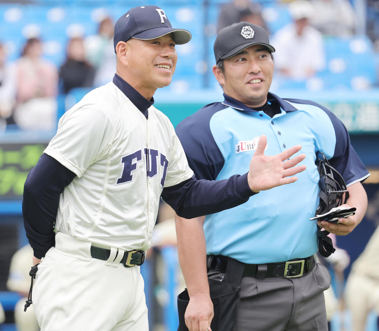 福井工大対桐蔭横浜大　佐伯球審（右）に選手交代を告げる福井工大・町田監督（撮影・野上伸悟）