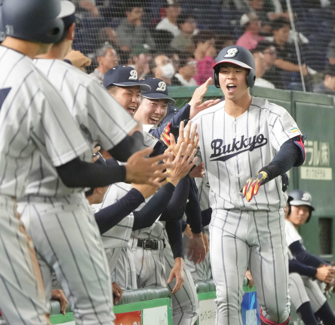 四国学院大対佛教大　3回裏佛教大1死三塁、岡野（右）は左越えに2点本塁打を放ちベンチのナインの祝福を受ける（撮影・小沢裕）