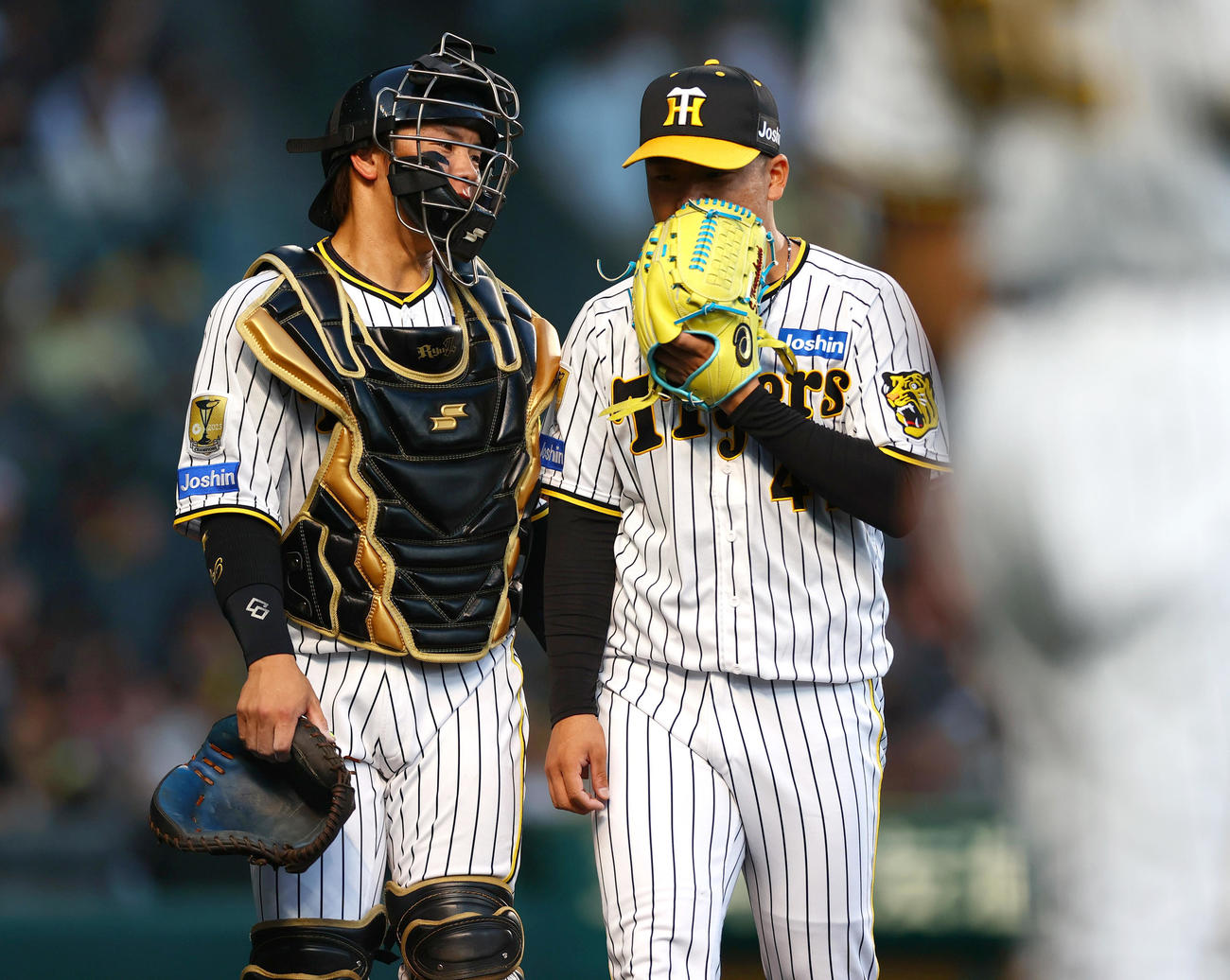阪神対日本ハム　4回表終了後、捕手梅野（右）の話を聞きながらベンチに引き揚げる阪神先発の村上（撮影・上山淳一）