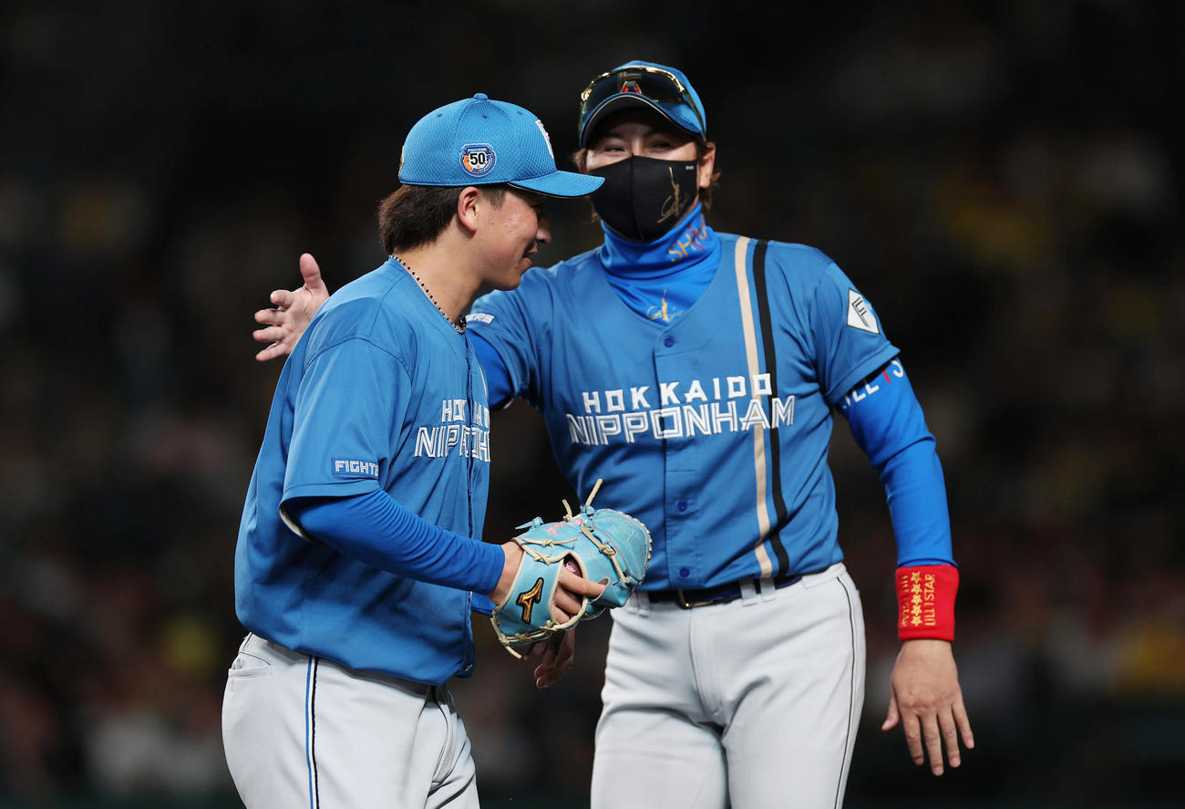 阪神対日本ハム　5回裏阪神1死一、二塁、小幡に四球を与えたところで降板となり、新庄監督（右）にタッチで迎えられる細野（撮影・前田充）