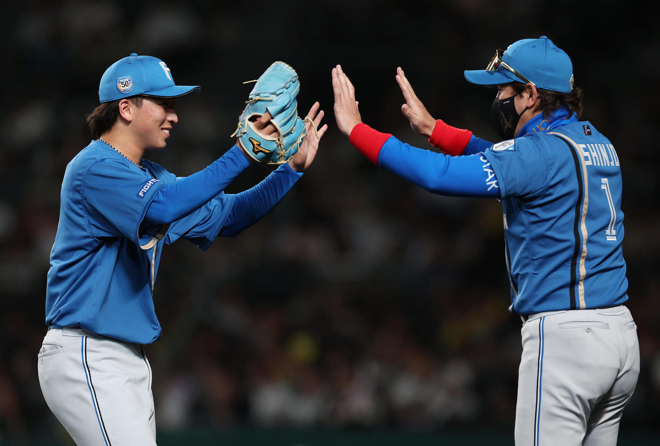 阪神対日本ハム　5回裏阪神1死一、二塁、小幡に四球を与えたところで降板となり、新庄監督（右）にタッチで迎えられる細野（撮影・前田充）