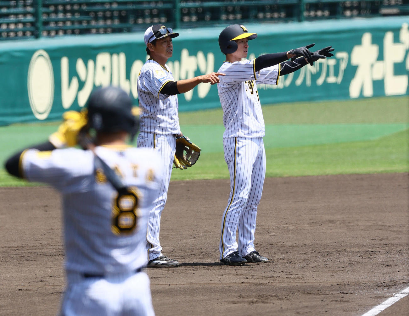 近本（右）はケース打撃で藤本コーチと話し合う。手前は佐藤輝（撮影・上山淳一）