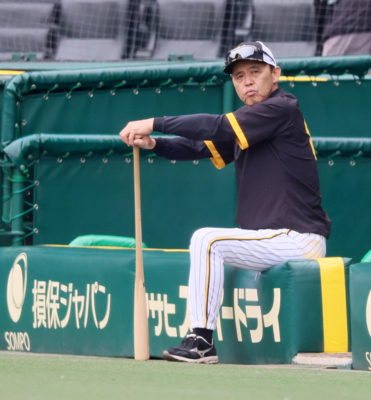 三塁側ベンチのラバーフェンスに座る岡田監督（撮影・加藤哉）