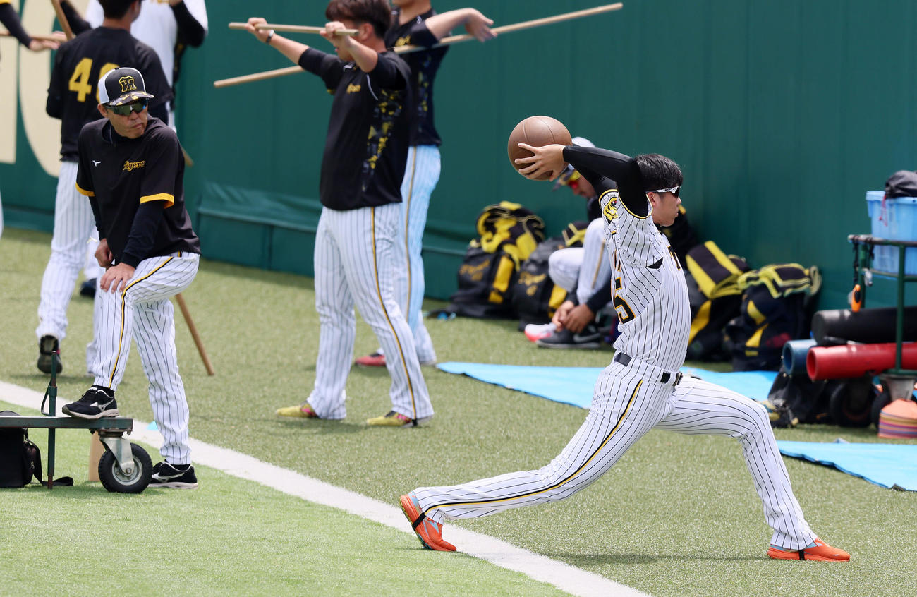阪神対DeNA　岡田監督（左）が見る前でメディシンボールを投げる才木（撮影・加藤哉）