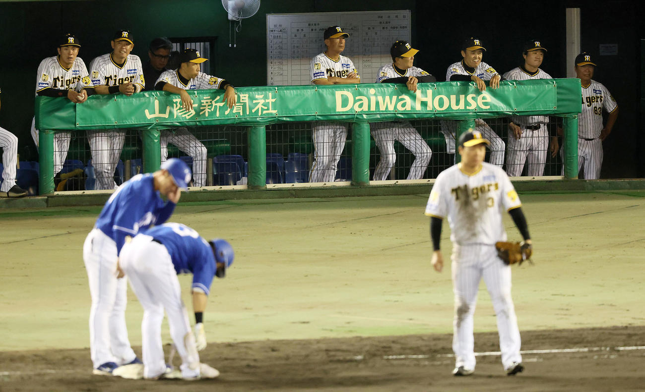 阪神対中日　8回表中日2死三塁、板山に右適時打を打たれベンチからグラウンドを見つめる岡田監督（右から3人目）（撮影・加藤哉）