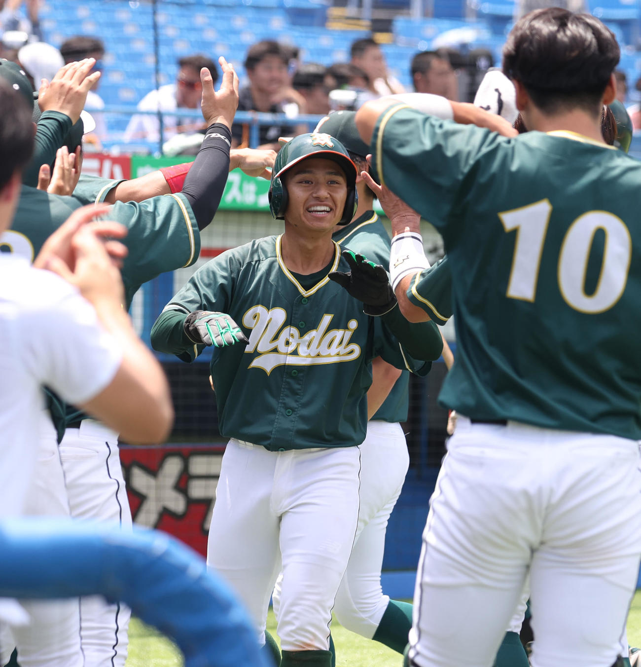 東農大対駒大　2回表東農大2死二、三塁、江川の中越え三塁打で生還した古川はナインの出迎えを受ける（撮影・柴田隆二）
