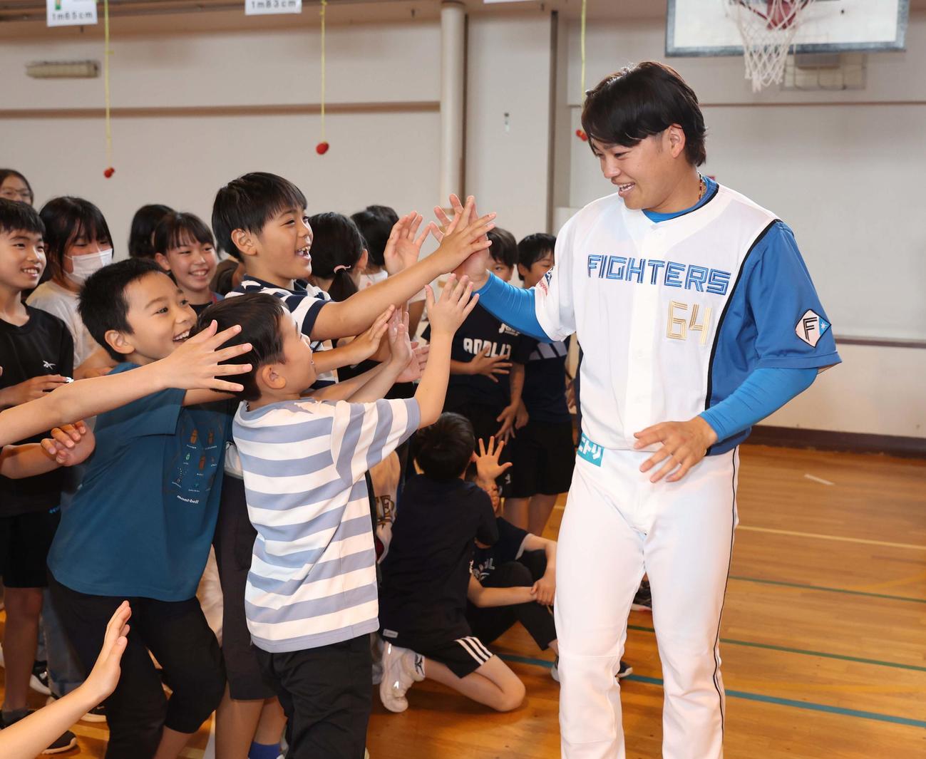 札幌市内の小学校を訪問し子どもたちとハイタッチする日本ハム田宮（撮影・黒川智章）