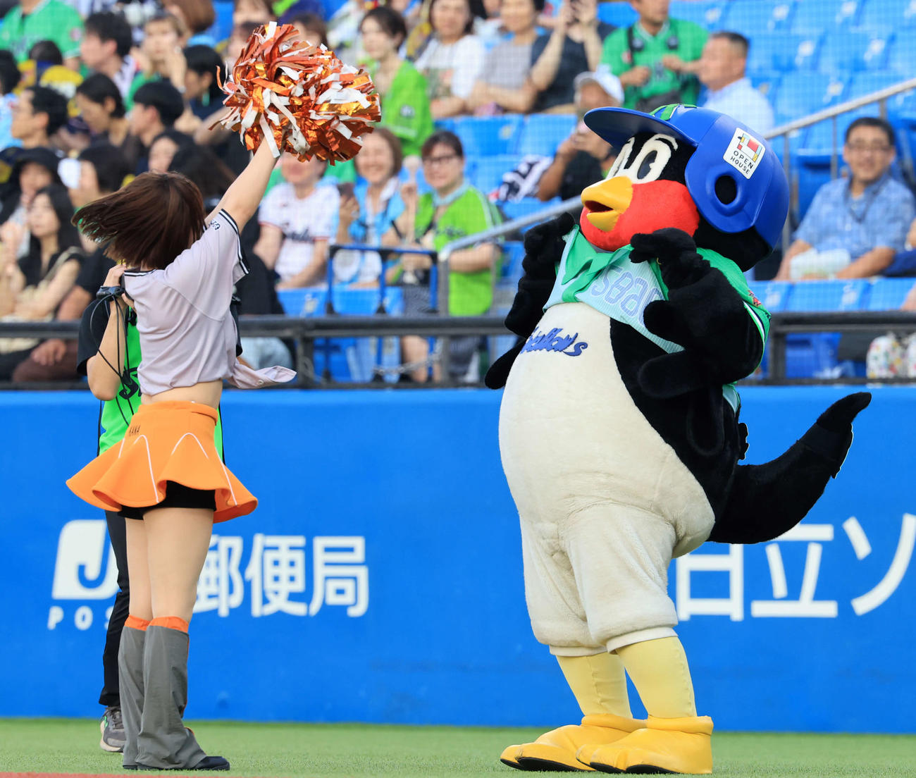 ヤクルト対巨人　試合前、ダンスを披露する巨人のヴィーナスに、ユニホームを上げて「スワローズ」の文字を見せるつば九郎（撮影・浅見桂子）