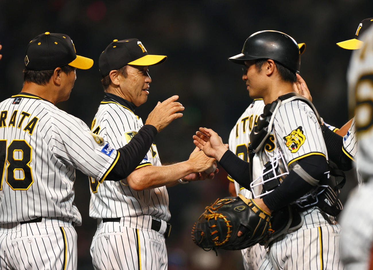 阪神対DeNA DeNAに勝利し阪神監督の歴代1位の通算515勝を挙げた岡田監督（左から2人目）は坂本からウイニングボールを受け取り笑顔を見せる（撮影・上山淳一）