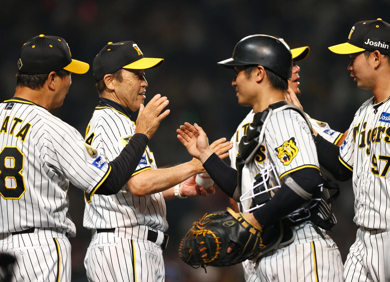 阪神対DeNA DeNAに勝利し阪神監督の歴代1位の通算515勝を挙げた岡田監督（左から2人目）は坂本からウイニングボールを受け取り笑顔を見せる（撮影・上山淳一）