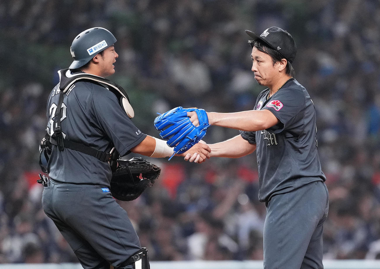 西武に勝利し、佐藤（左）と握手をするロッテ益田（撮影・菅敏）