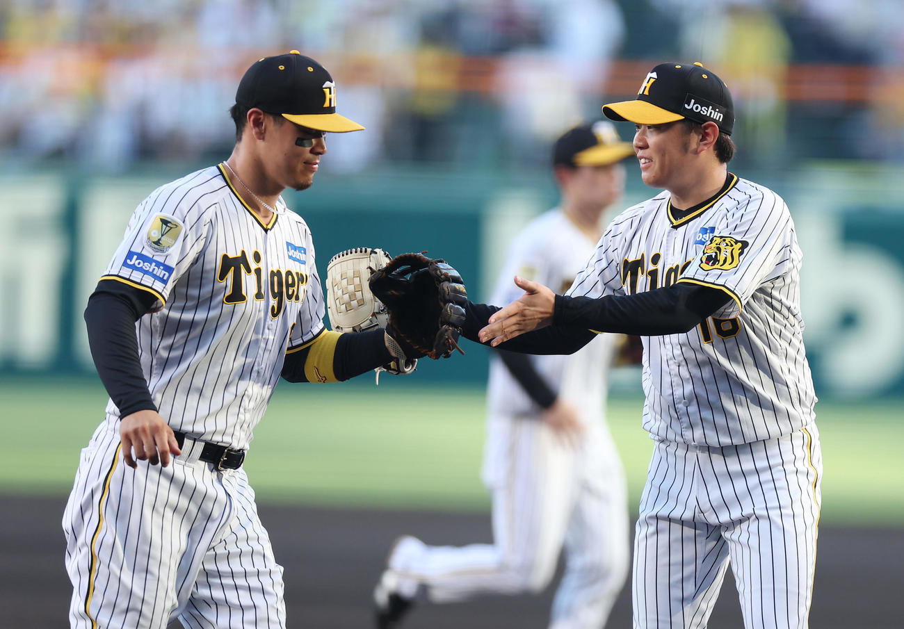 阪神対DeNA 1回表を投げ終え、阪神佐藤輝（左）とタッチを交わす西勇（撮影・前田充）