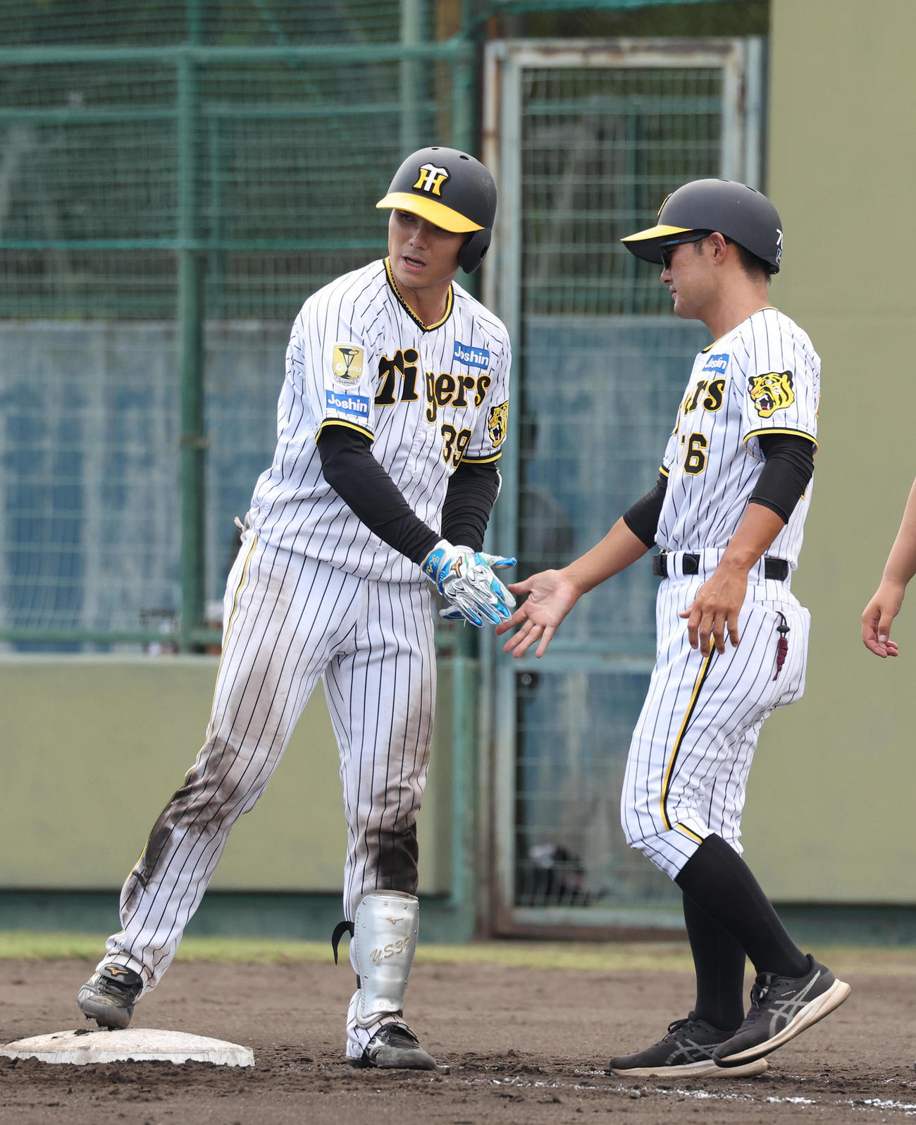 ウエスタンリーグ阪神対くふうハヤテ　7回裏阪神1死二塁、栄枝（左）は中前適時打を放ち工藤コーチとタッチを交わす（撮影・白石智彦）