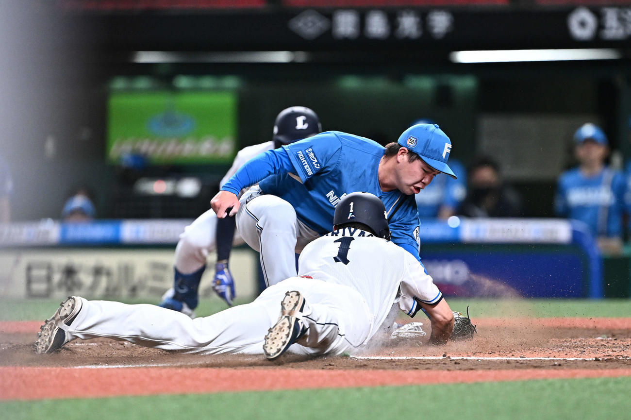 西武対日本ハム　2回裏西武2死三塁、金村（中央）は本塁にカバーに入り栗山（手前）の生還を阻む（撮影・滝沢徹郎）