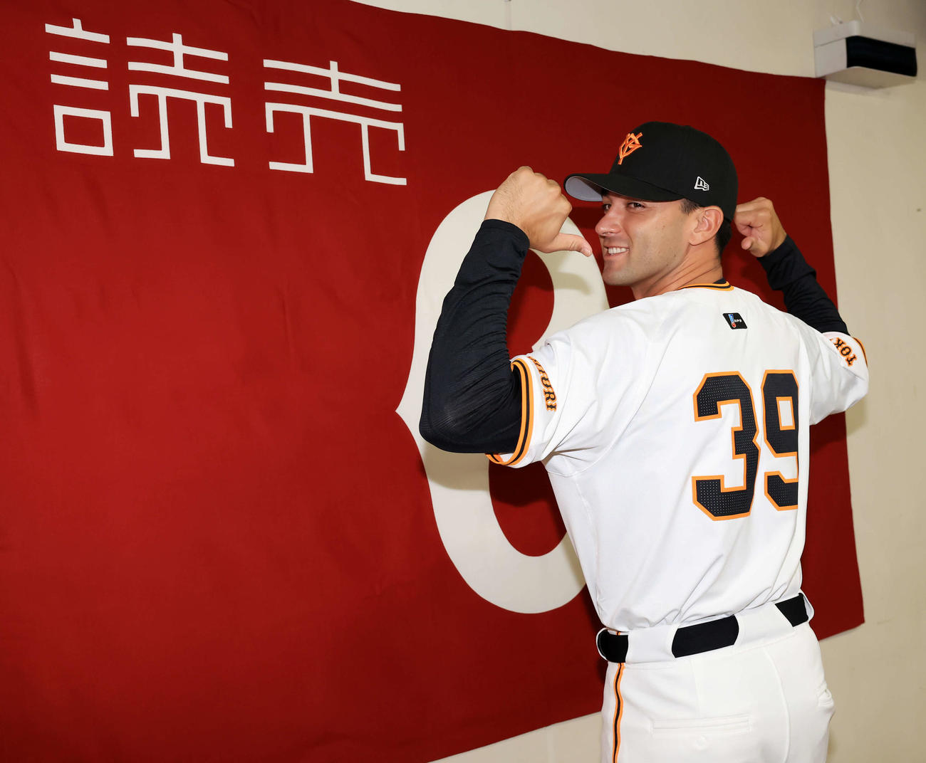 巨人入団会見で、笑顔で背番号を指さすモンテス（撮影・浅見桂子）