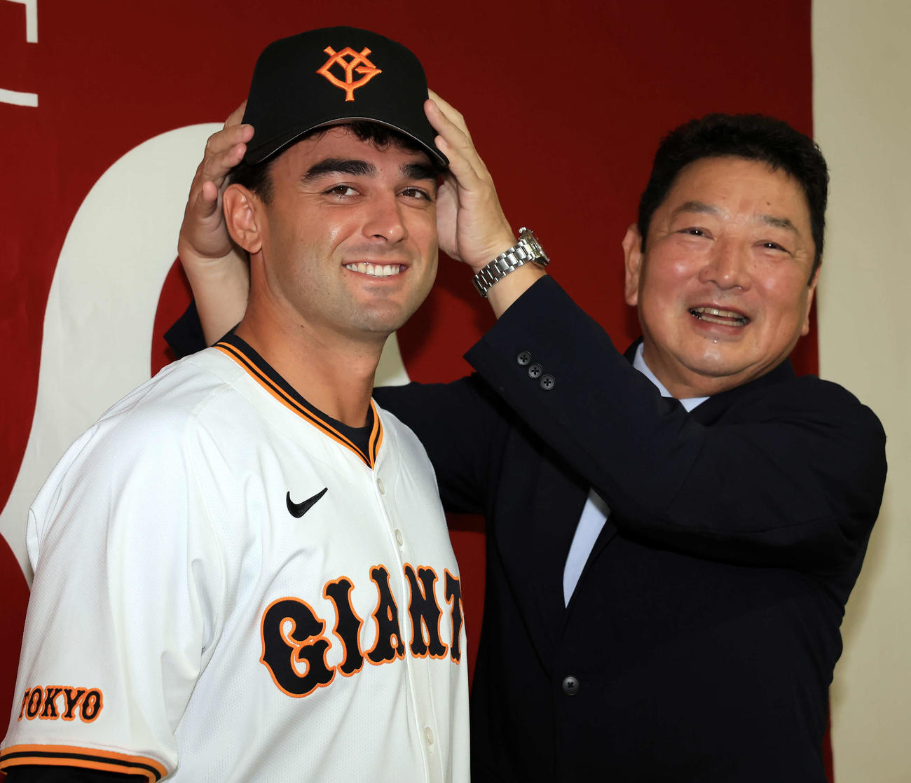 巨人入団会見で、吉村禎章編成本部長（右）から帽子をかぶせてもらうモンテス（撮影・浅見桂子）