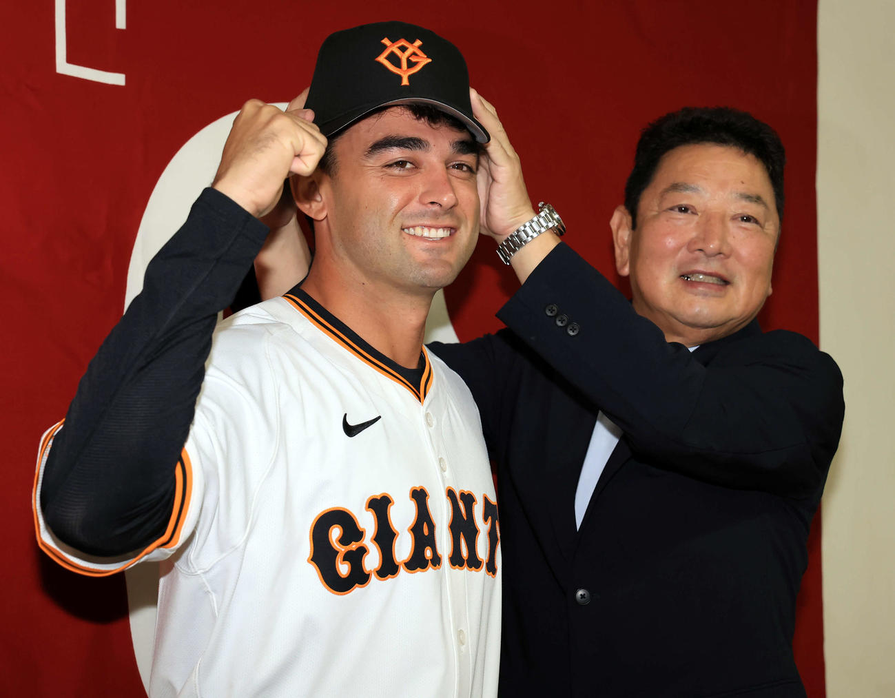 巨人入団会見で、吉村禎章編成本部長（右）から帽子をかぶせてもらうモンテス（撮影・浅見桂子）