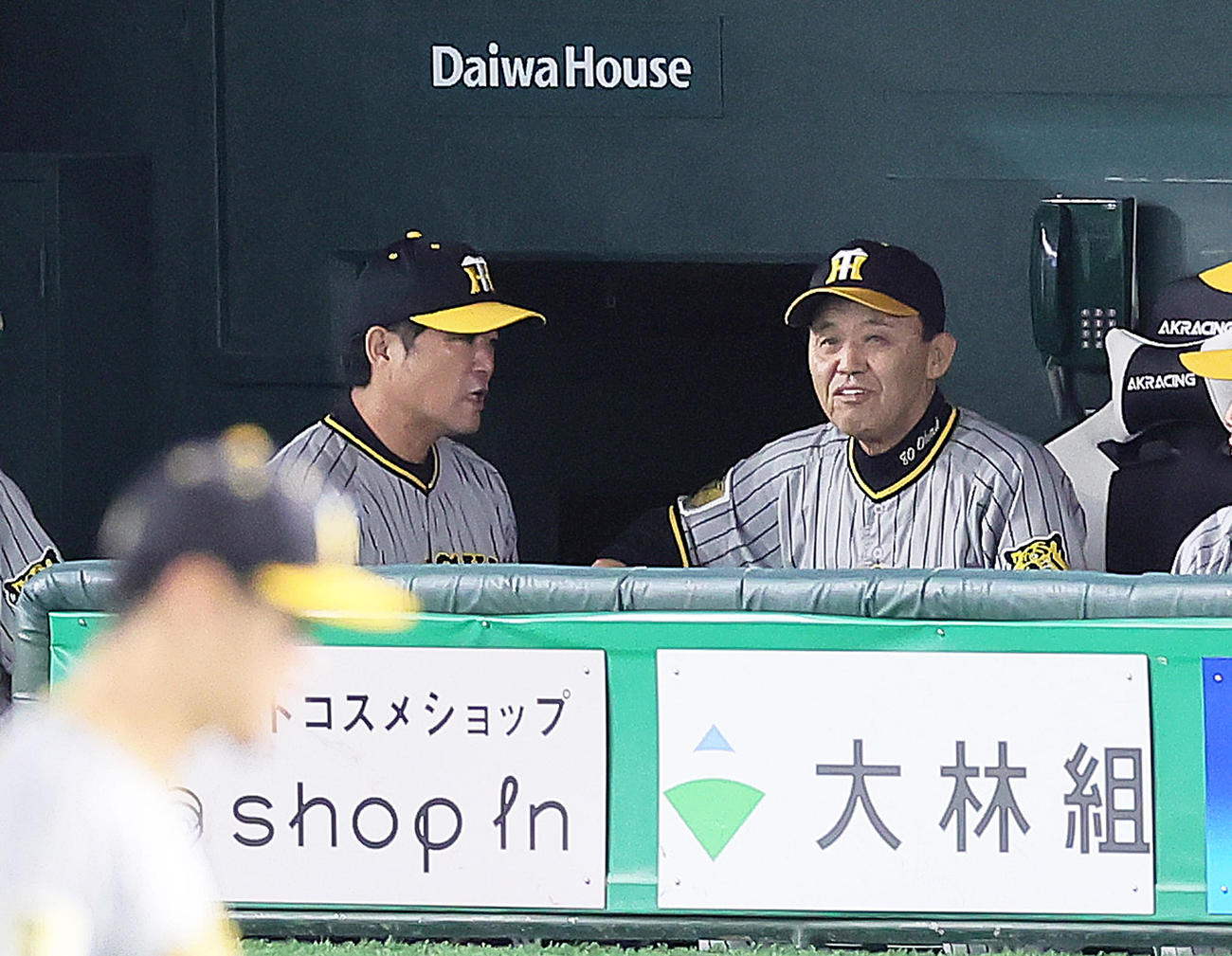 巨人対阪神　8回、マウンドの阪神才木のもとへ向かった安藤コーチ（左）の話を聞き、思わず笑みを浮かべる岡田監督（撮影・足立雅史）