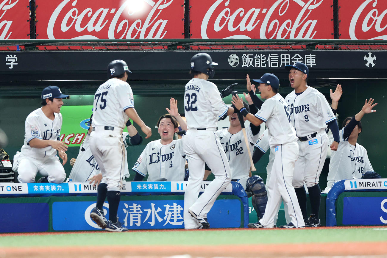 西武対オリックス　6回裏西武1死一、三塁、山村（中央）の中犠飛で生還する奥村（左）を迎えるチームメート（撮影・河田真司）