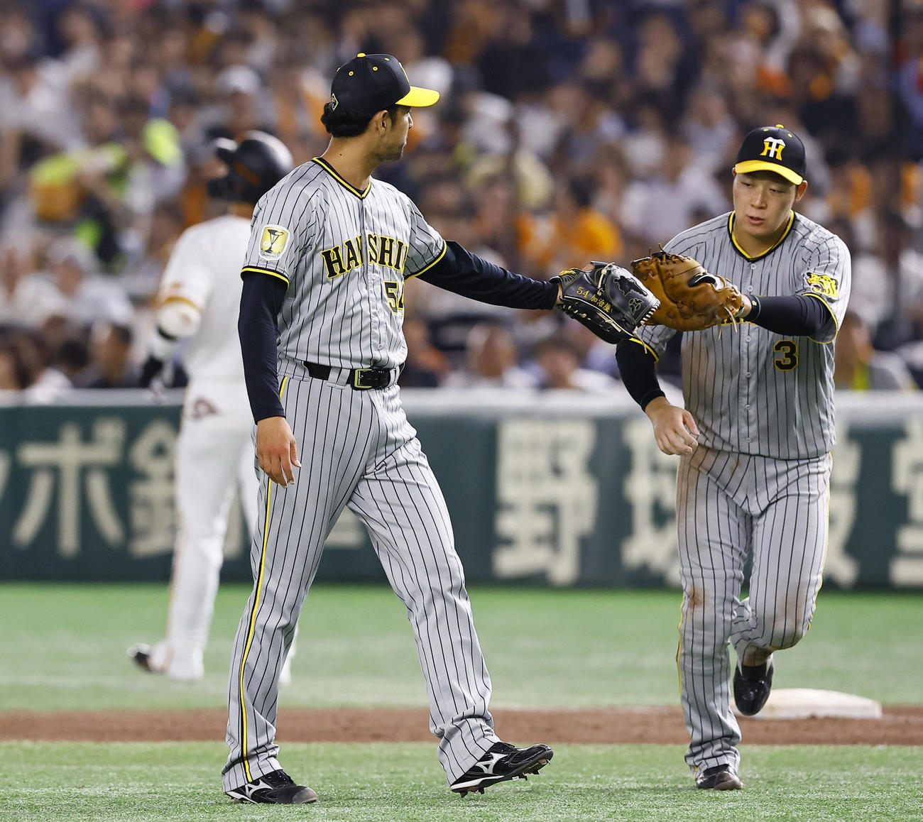 巨人対阪神　8回裏巨人1死一塁、坂本を一ゴロ併殺に打ち取り加治屋蓮（左）とタッチを交わす大山（撮影・藤尾明華）