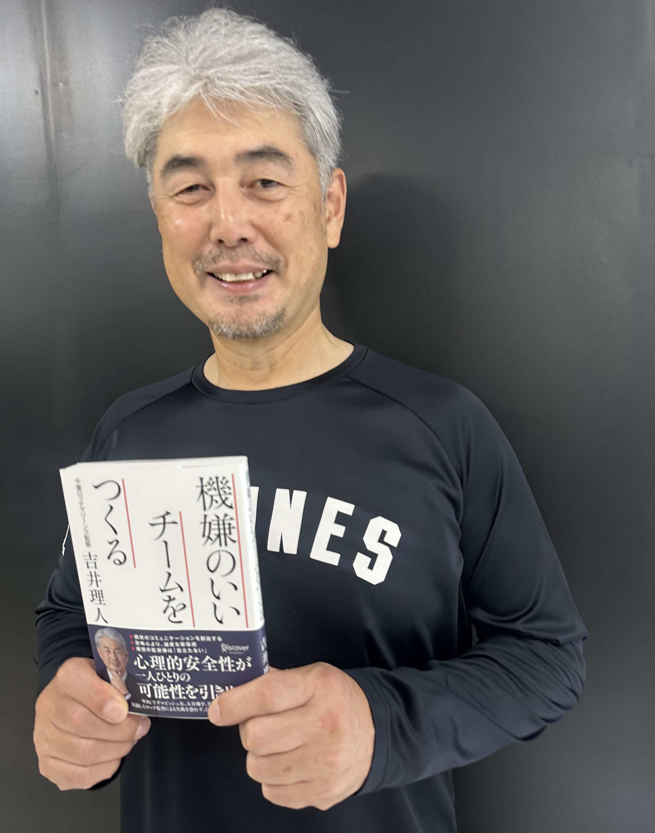 著書の『機嫌のいいチームをつくる』を手に笑顔の吉井監督（球団提供）