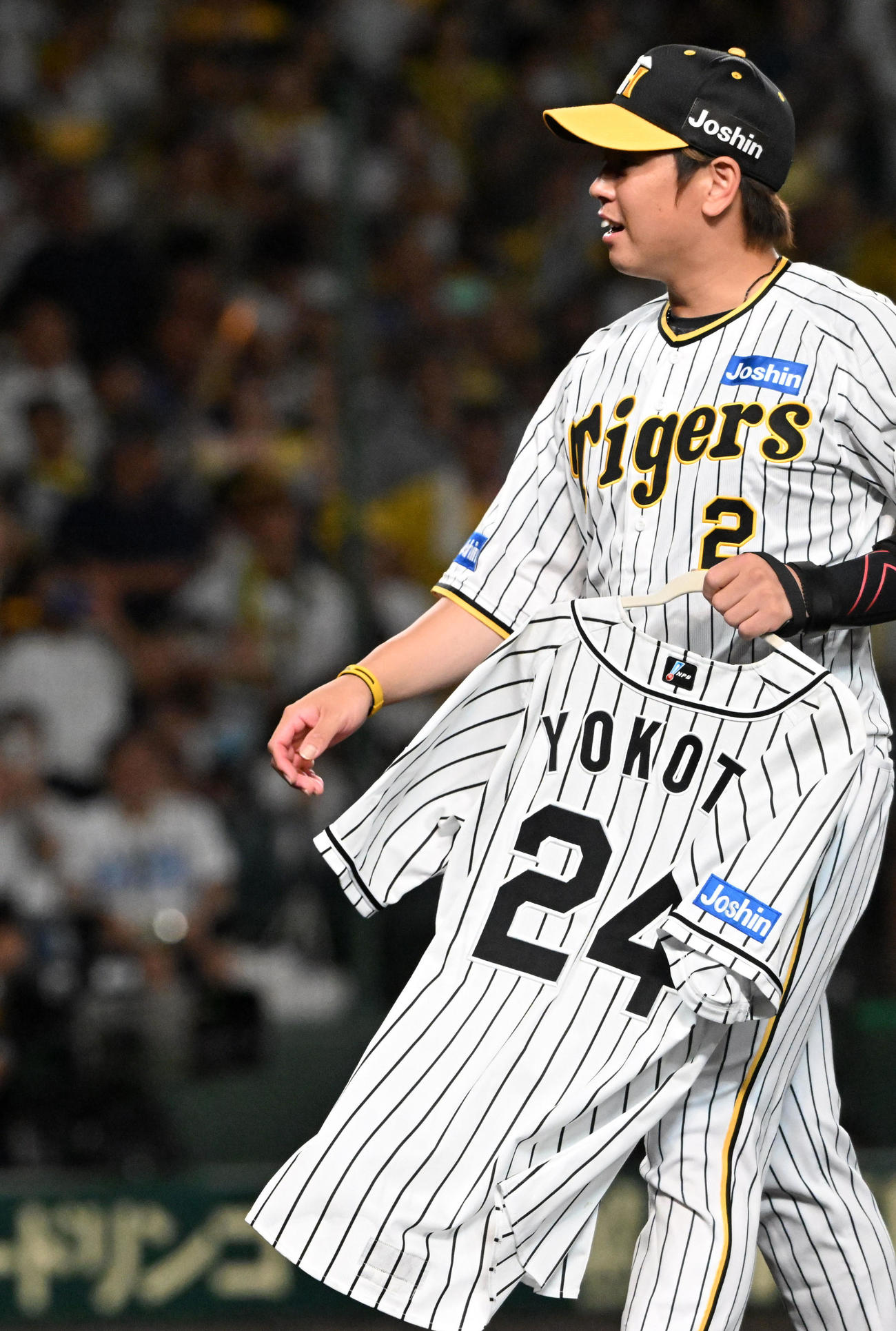 横田慎太郎さんのユニホームを手に笑顔を見せる梅野隆太郎（2023年9月14日撮影）