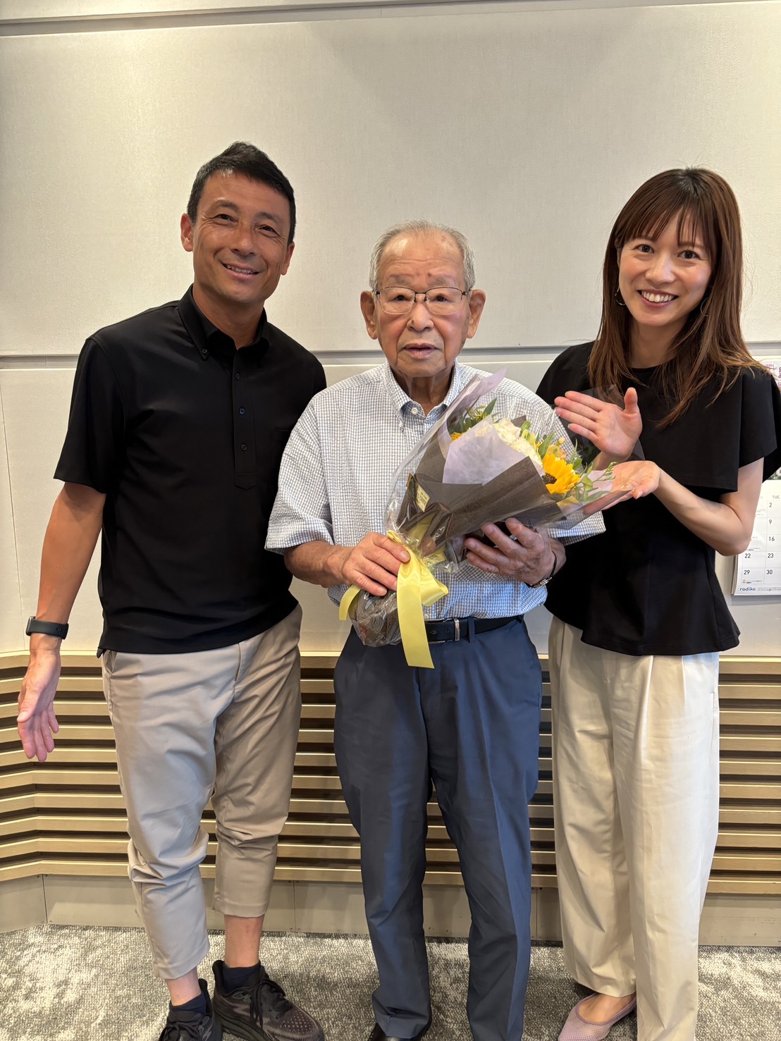 ABCアナウンサー小縣裕介氏と板垣奈津美さんから、91歳になった誕生日祝いの花束を贈られる吉田義男氏（中央）