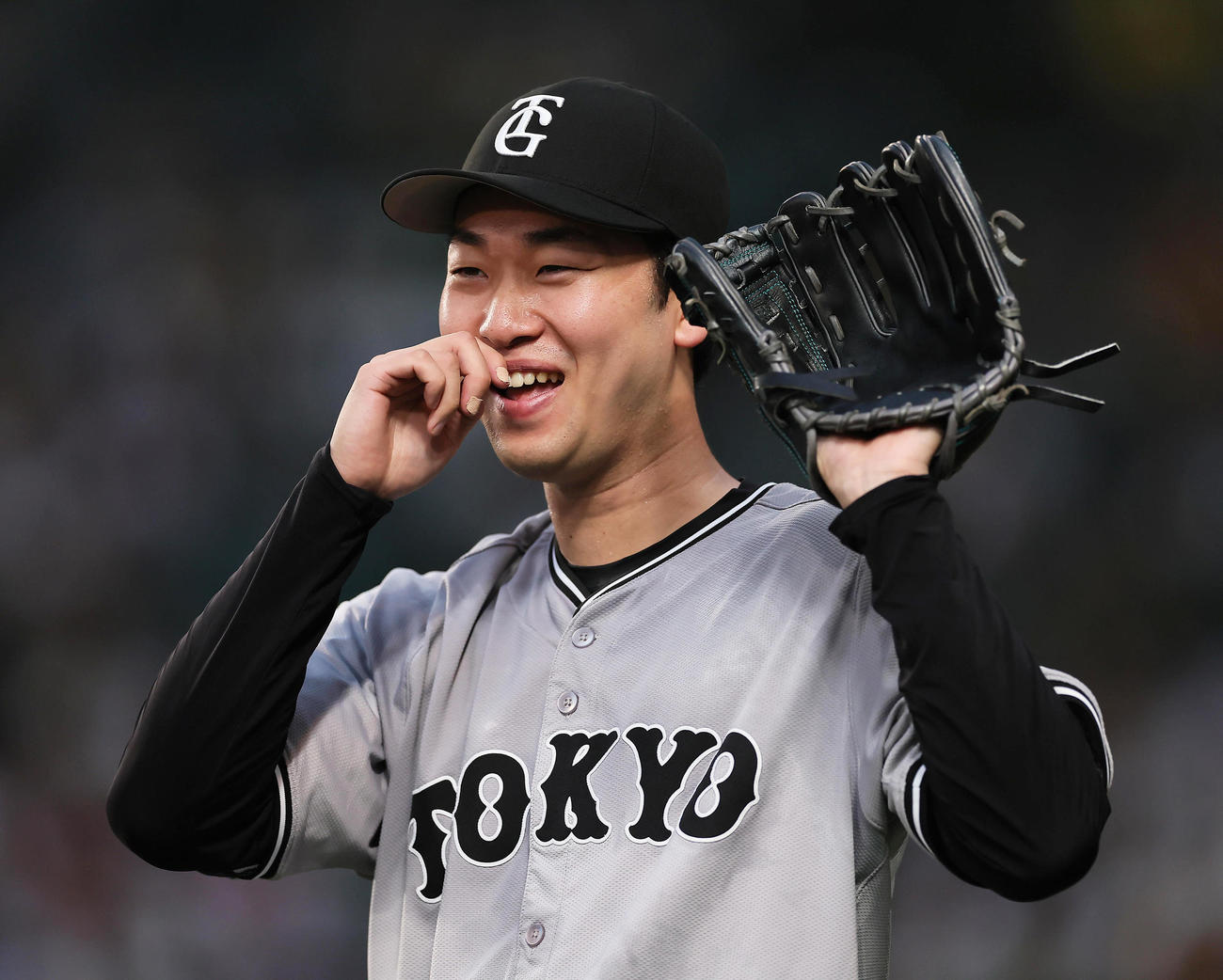 阪神隊巨人　投球練習中に飛んできたボールをキャッチし、スタンドの声援に笑顔を見せる巨人山崎伊（撮影・足立雅史）