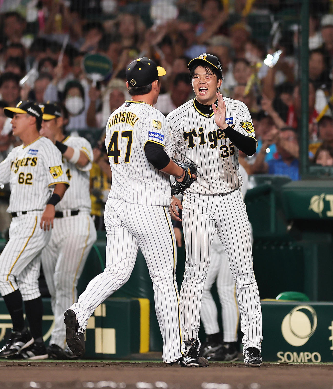 阪神隊巨人　7回表巨人2死一、三塁、代打坂本を見逃し三振に抑えた後続の桐敷（左）をタッチで迎える才木（撮影・足立雅史）