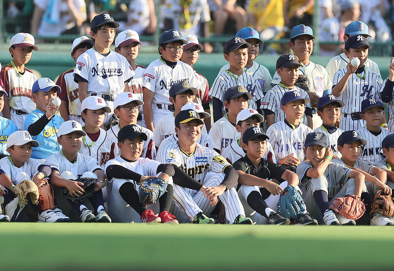 試合前「少年少女100球ファーストピッチ」を行った子どもたちとの記念撮影に笑顔を見せる阪神村上（手前中央）（撮影・足立雅史）