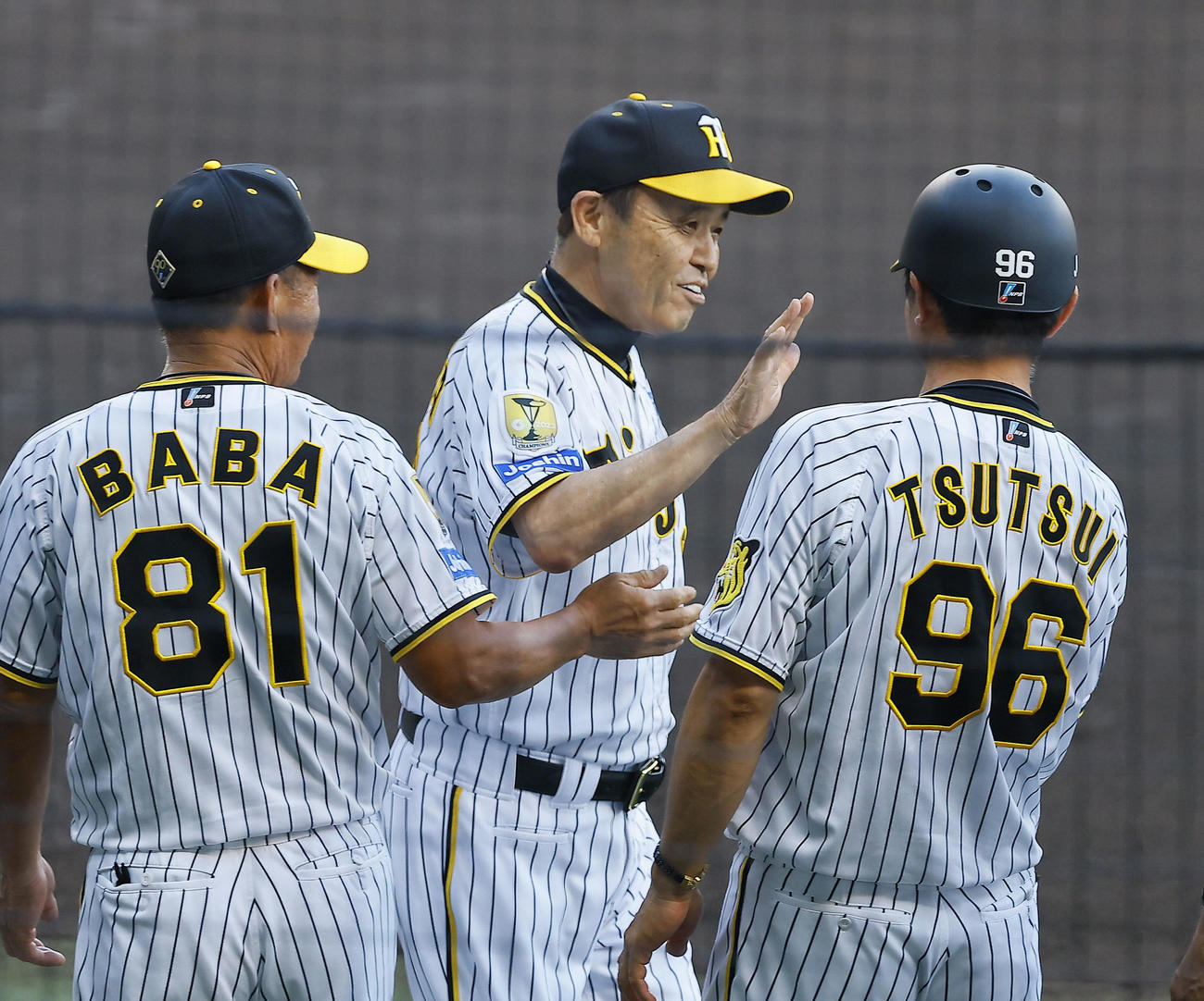 阪神対巨人　監督通算700勝を達成し、記念のメダルを贈られ、ベンチ前でタッチを交わす阪神岡田監督（撮影・藤尾明華）
