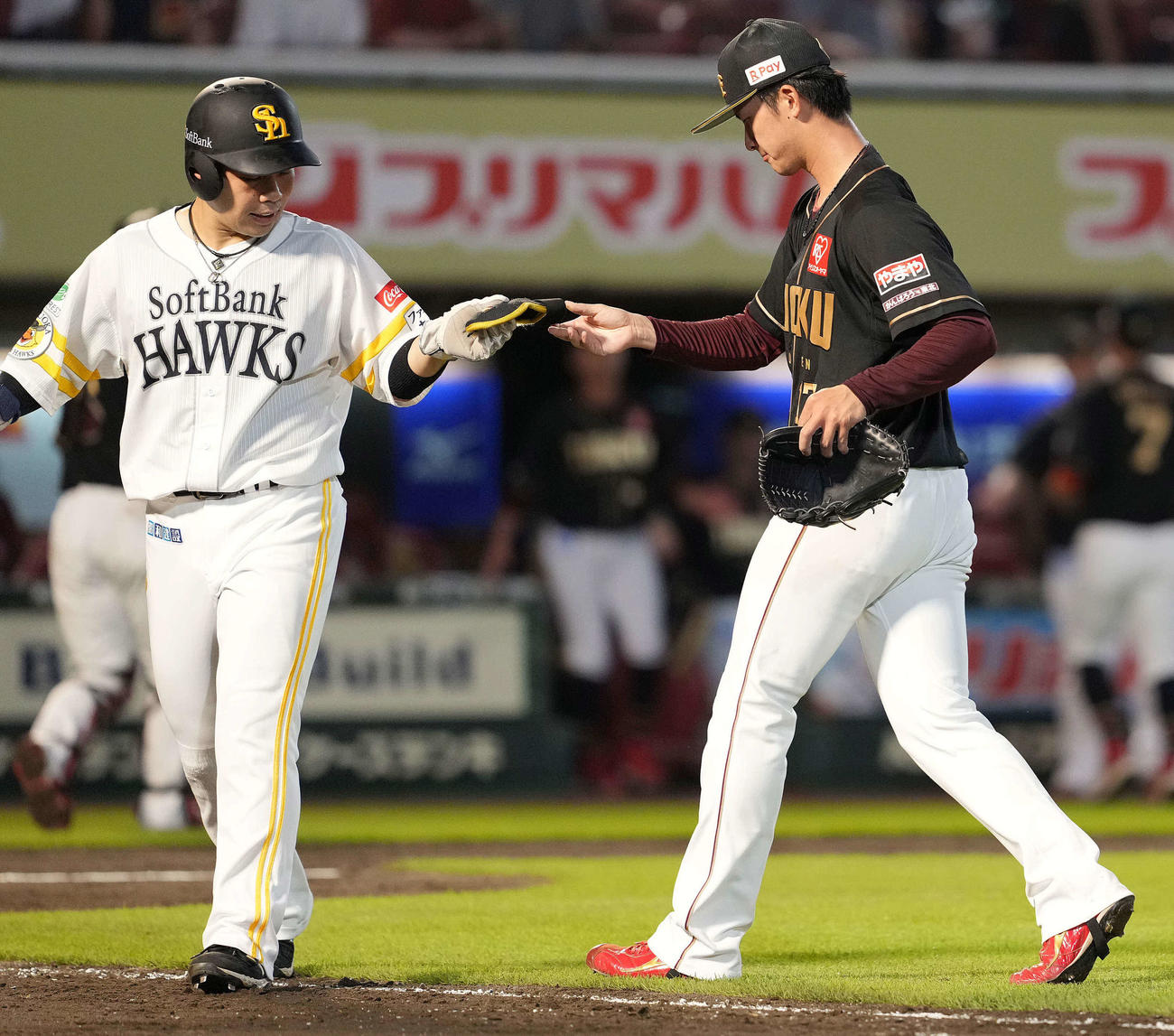 楽天対ソフトバンク　4回表を終え、正木の防具を拾ってソフトバンク近藤（左）に渡す楽天古謝（撮影・鈴木みどり）