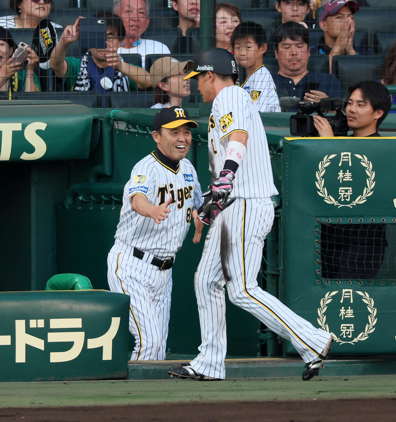 阪神対巨人　1回裏阪神2死満塁、及川の左適時打で本塁走塁死の木浪（右）を笑顔で出迎える岡田監督（撮影・加藤哉）