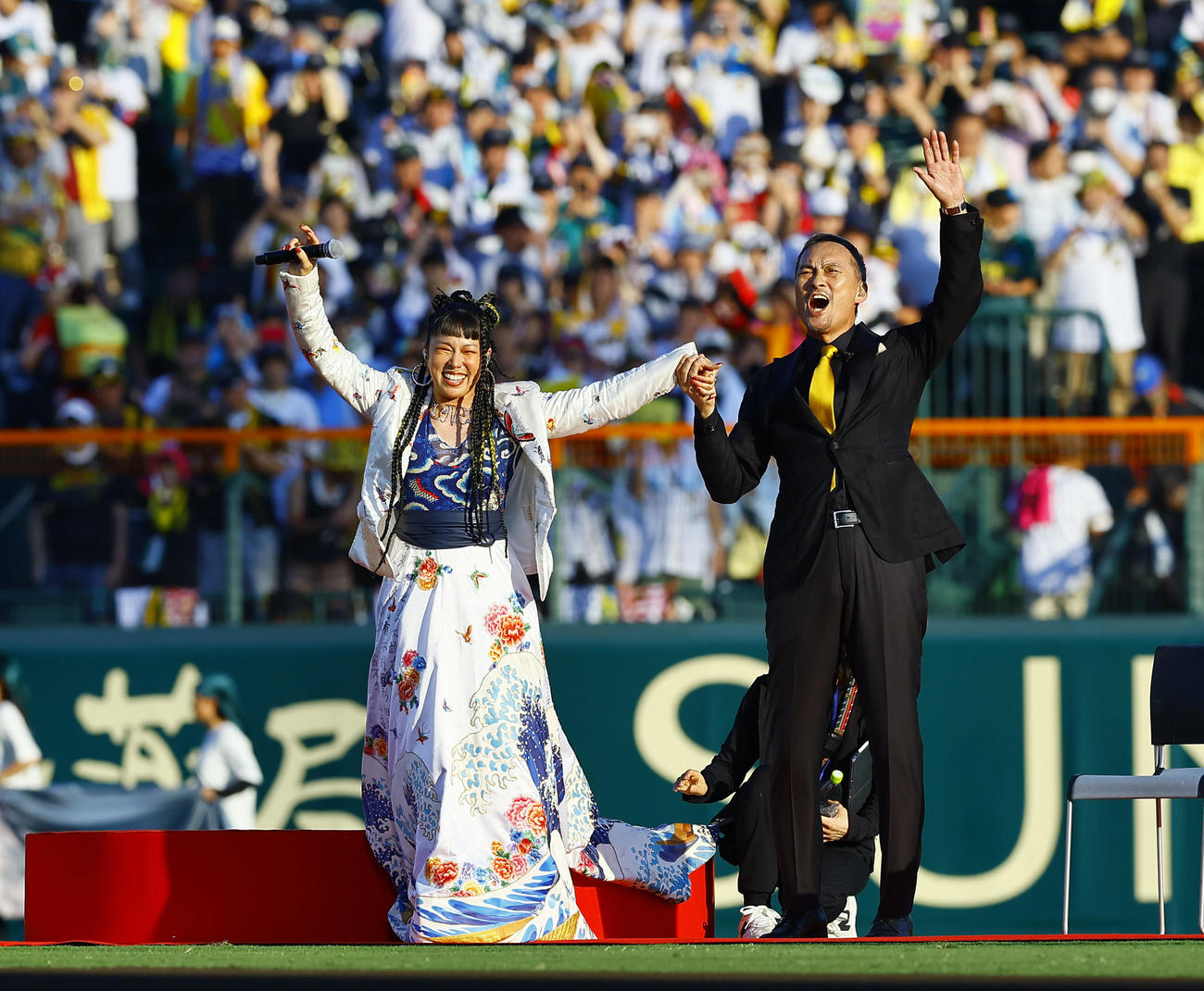 阪神対巨人　100周年セレモニーを盛り上げる歌手のAIさん（左）と俳優の渡辺謙さん（撮影・藤尾明華）