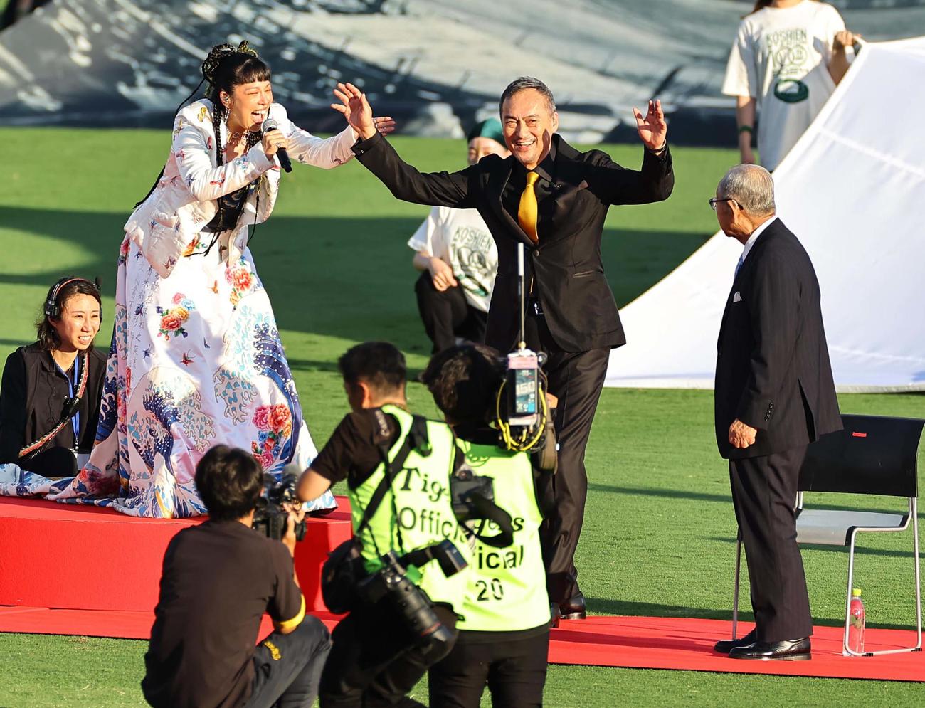 阪神対巨人　甲子園100周年のステージで歌うAI（左）と笑顔を見せる渡辺謙（撮影・上田博志）