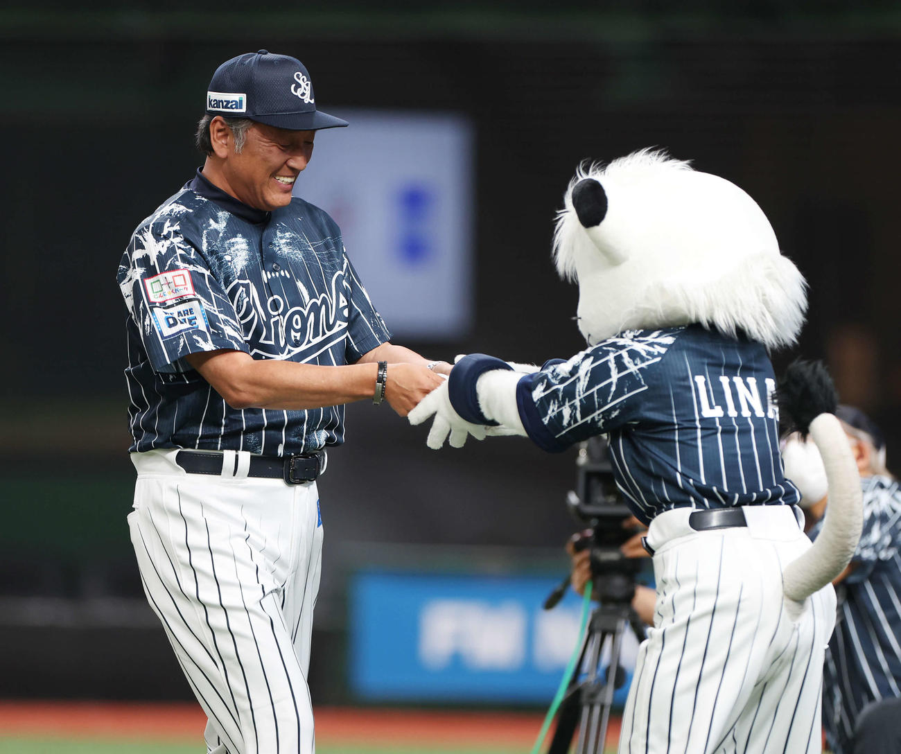西武対楽天　試合前、西武マスコットのライナ（右）に笑顔でメンバー表を渡す渡辺GM兼監督代行（撮影・宮地輝）