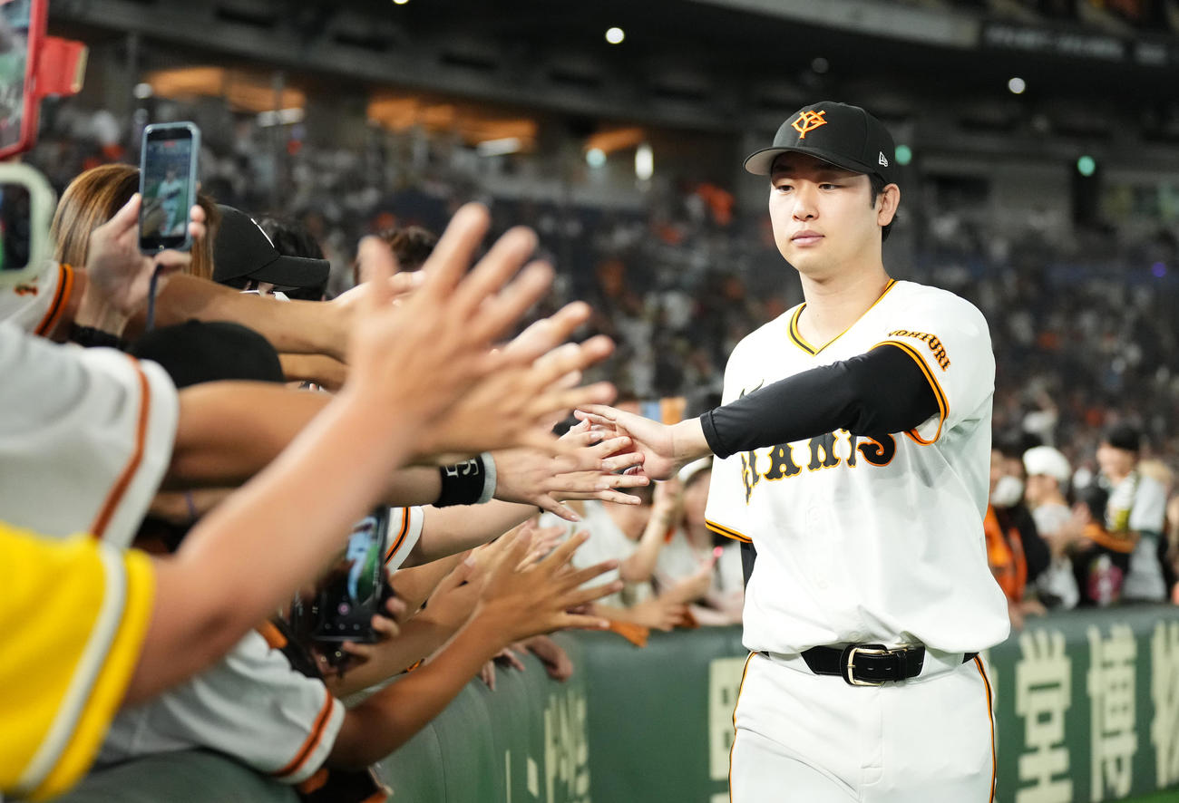 巨人対阪神　阪神に勝利し、ファンとタッチをする巨人山崎伊（右）（撮影・菅敏）